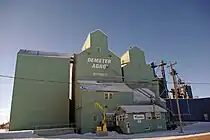 Two green elevators in winter, against a blue sky