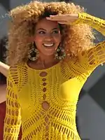 Woman with blonde curly hair wearing a yellow outfit