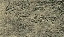 Black and white image of ancient stone-carved writing.