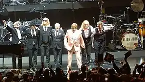 The Elton John Band after performing in November 2018. From left to right: Ray Cooper, Matt Bissonette, Kim Bullard, Nigel Olsson, Elton John, Davey Johnstone, and John Mahon