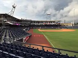 A baseball stadium with navy blue seats surrounds a green baseball field