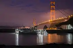 47-foot Motor Lifeboat moored at Coast Guard Station Golden Gate at night. Station Golden Gate is located on the grounds of Fort Baker in Sausalito, California, and the illuminated Golden Gate Bridge is visible in the background.