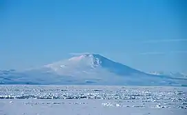 Distant view over an ice-covered sea of a conical mountain