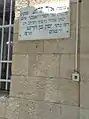Stone commemorative plaque on the exterior wall stating: Yeshiva donated by Mr Yamin Ben Harroch in 1927.