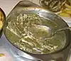 Eel meat in a green herb sauce in a metal serving dish