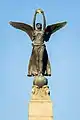 Winged figure holding a golden crown at the top of the obelisk