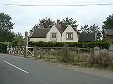 fac-on view of the station building with its two dormer windows. At some point since conversion to a house it has been whitewashed. Just visible on the right of the house is the red brick gable of the former goods shed