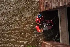 A Coast Guard Aviation Survival Technician assisting with the rescue of a pregnant woman during Hurricane Katrina in 2005