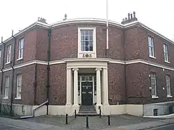 A Neogothic brick house with stone dressings and a curved porch on a street corner