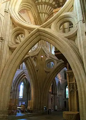 A huge undecorated Gothic arch spans the width of the cathedral nave, with an inverted arch above it, giving  scissors-like appearance
