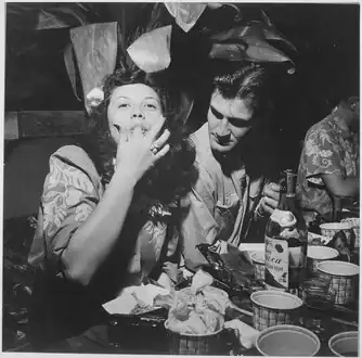 Navy pilots relax and enjoy feminine companionship, sports and entertainment at Chris Holmes Rest Home, maintained for pilots on leave from combat. Fingers replace forks at chow-time. Hawaii, March 1944.